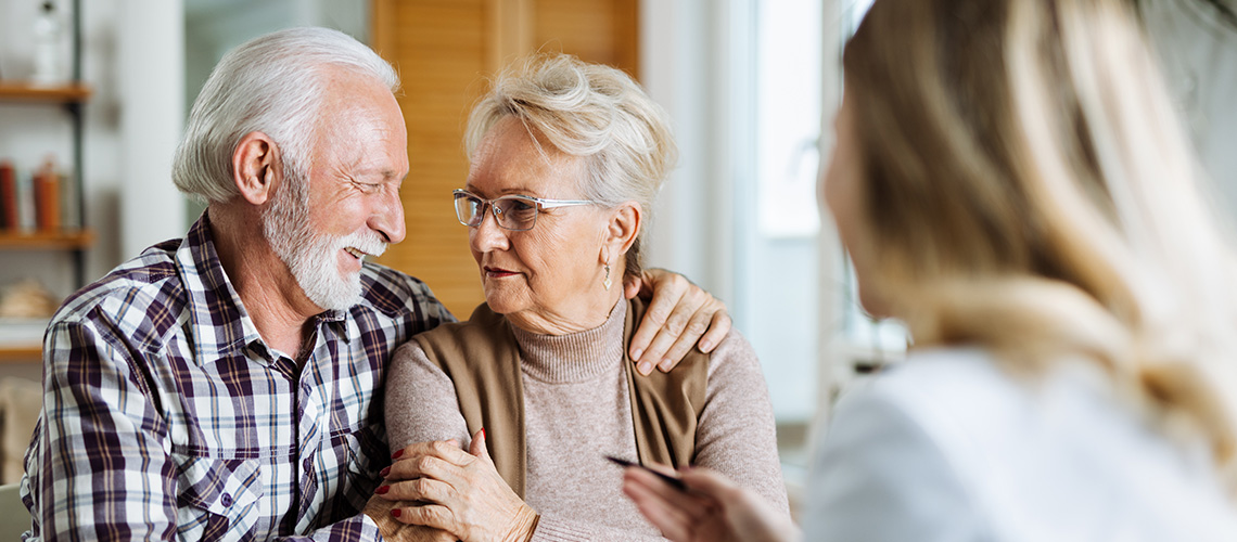 Älteres Ehepaar schaut sich liebevoll an, im Vordergrund eine Frau